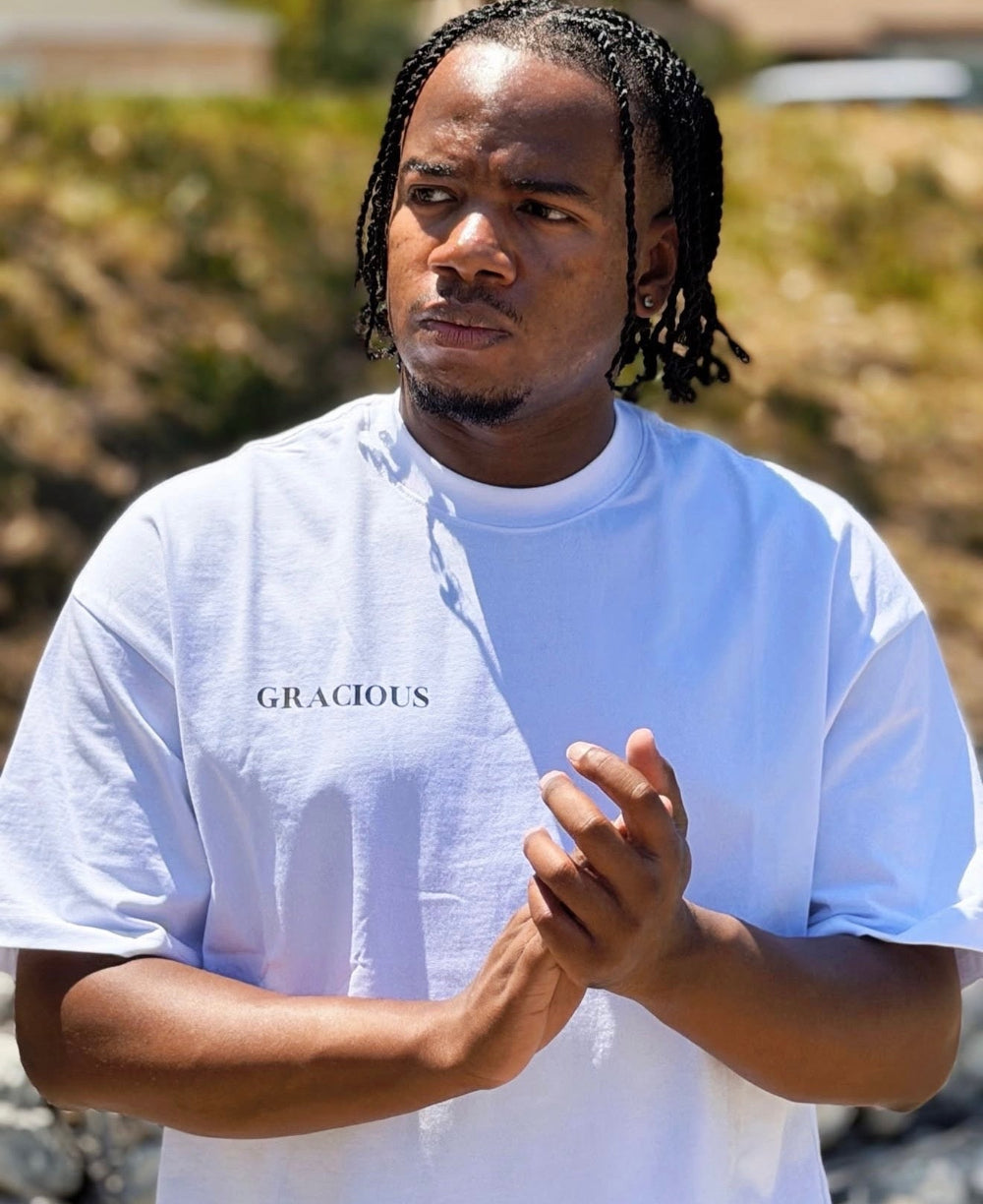 Person wearing a white 'GRACIOUS' t-shirt outdoors